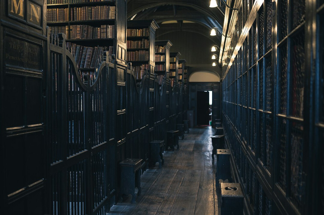 Old library with tall wooden shelves and archival boxes in dim light